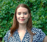 Johnston headshot outside with greenery background